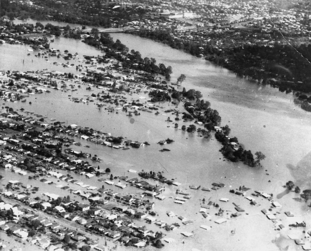 This image depicts an aerial view of the Indooroopilly Reach of the Brisbane River, showing the submerged houses and trees due to cyclone wanda. 'John Oxley Library, State Library of Queensland Image: 180235'.