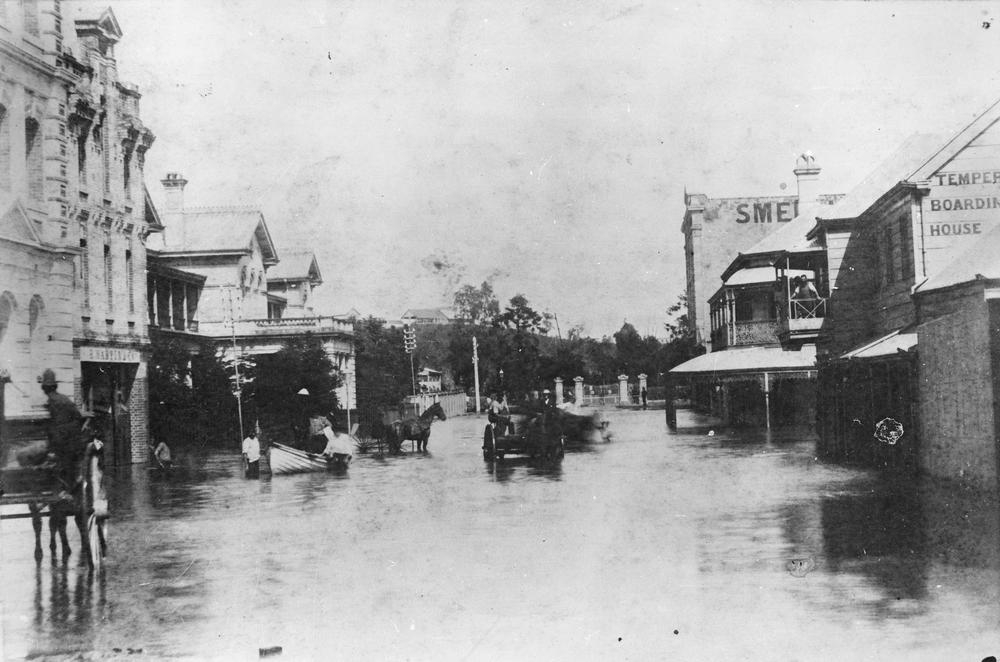View of floodwater in Edward Street, between Mary and Margaret Streets, looking towards the entrance of the Botanic Gardens. 'John Oxley Library, State Library of Queensland  Image:22225'.