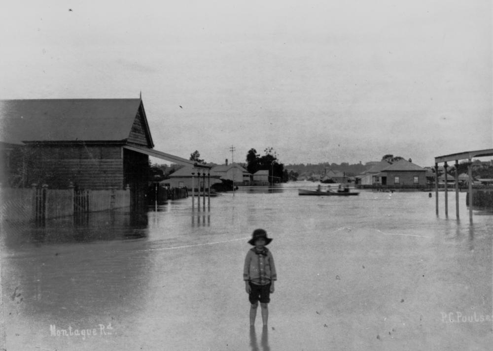 Child standing ankle deep in flooded Montague Road, West End, Brisbane, 1890. 'John Oxley Library, State Library of Queensland   Image:66105'.